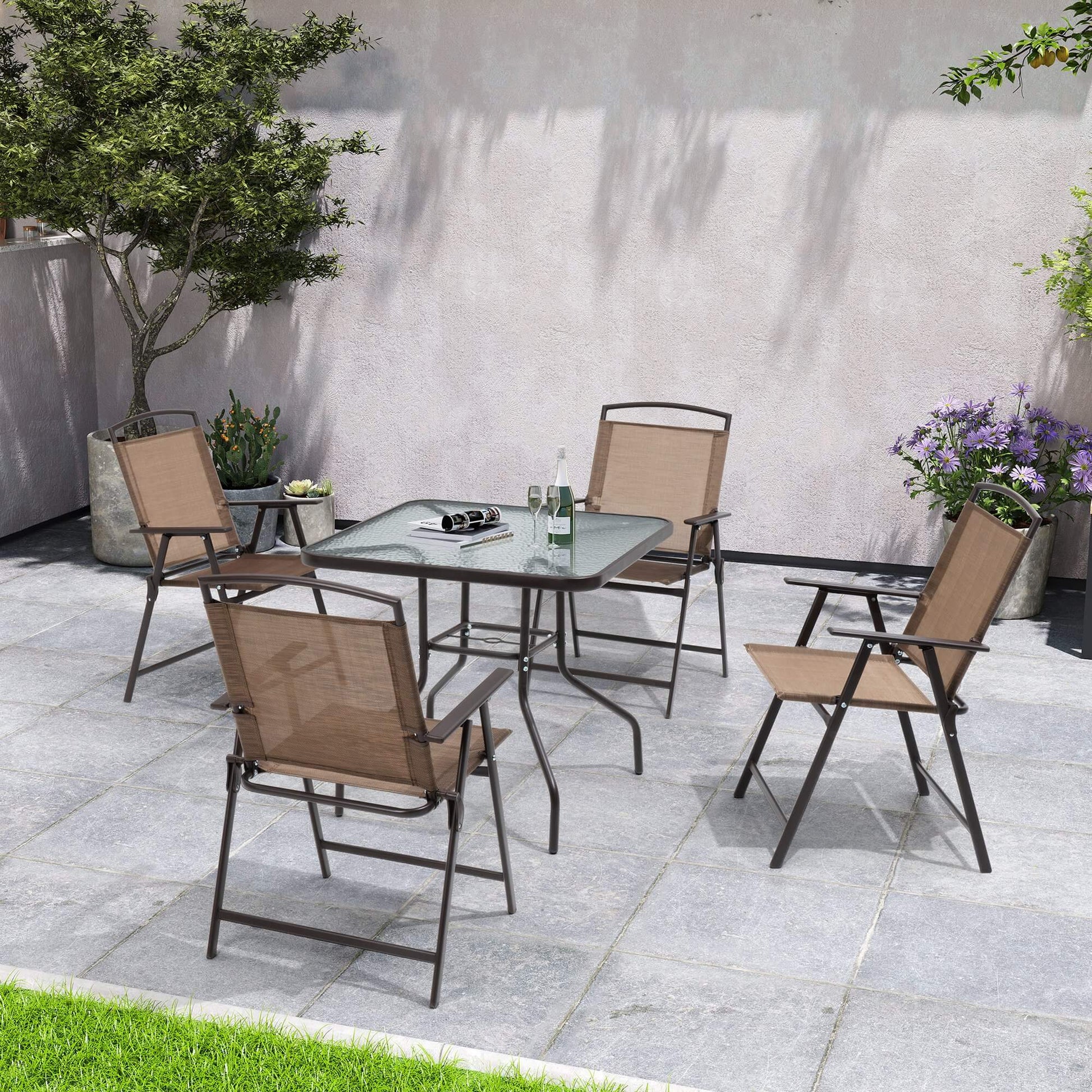 5-piece patio dining set with glass top table and 4 folding chairs on a backyard stone patio.