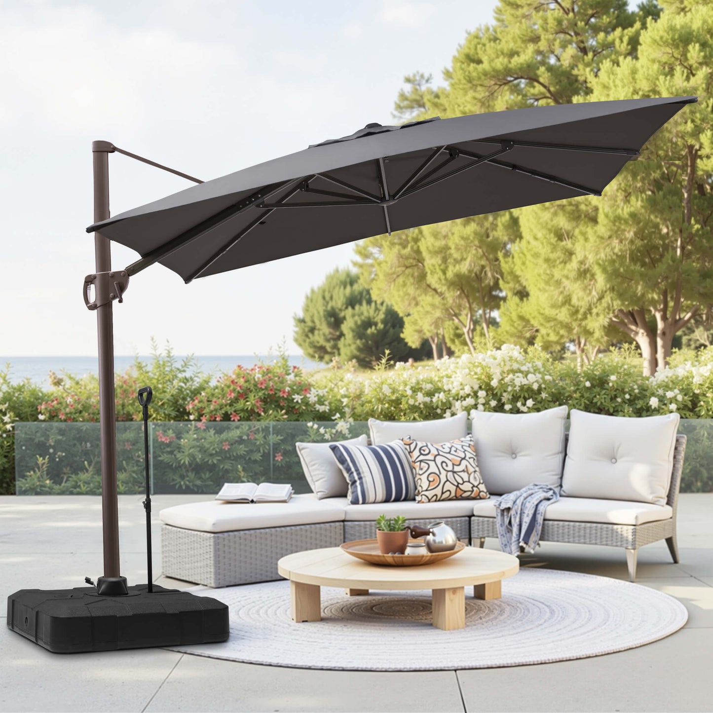 Grey rectangular cantilever umbrella with weighted pull-rod base over patio lounge seating.
