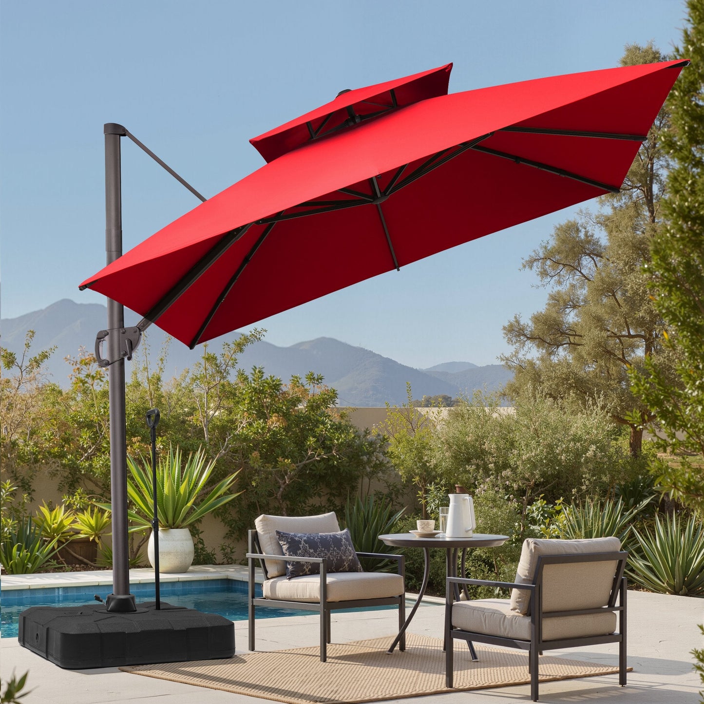 Tilted 10x10 ft square red cantilever patio umbrella with wheeled base shading a poolside seating set