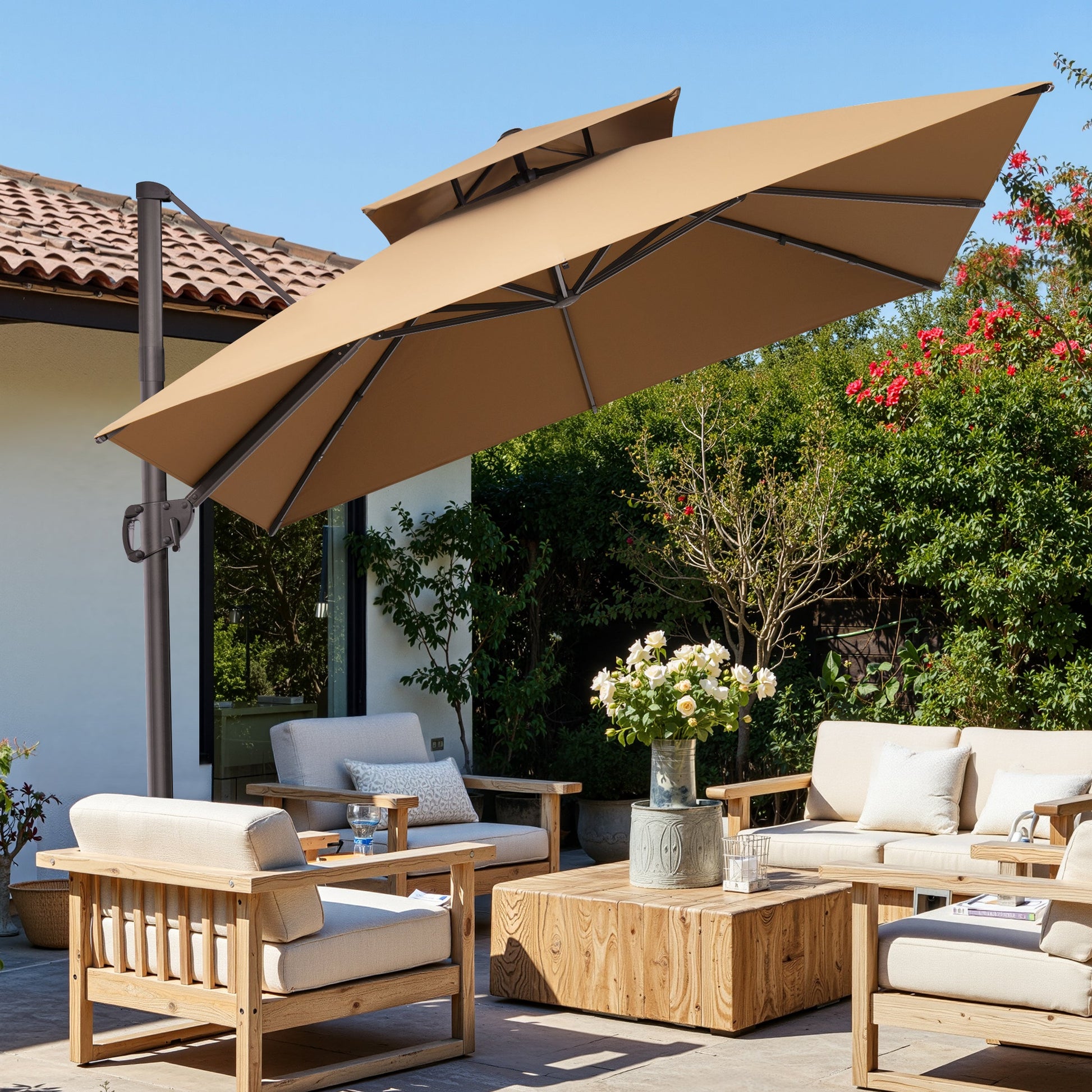 Tilted 10x10 ft square beige cantilever umbrella with cross base shading a patio wooden sofa set in daylight