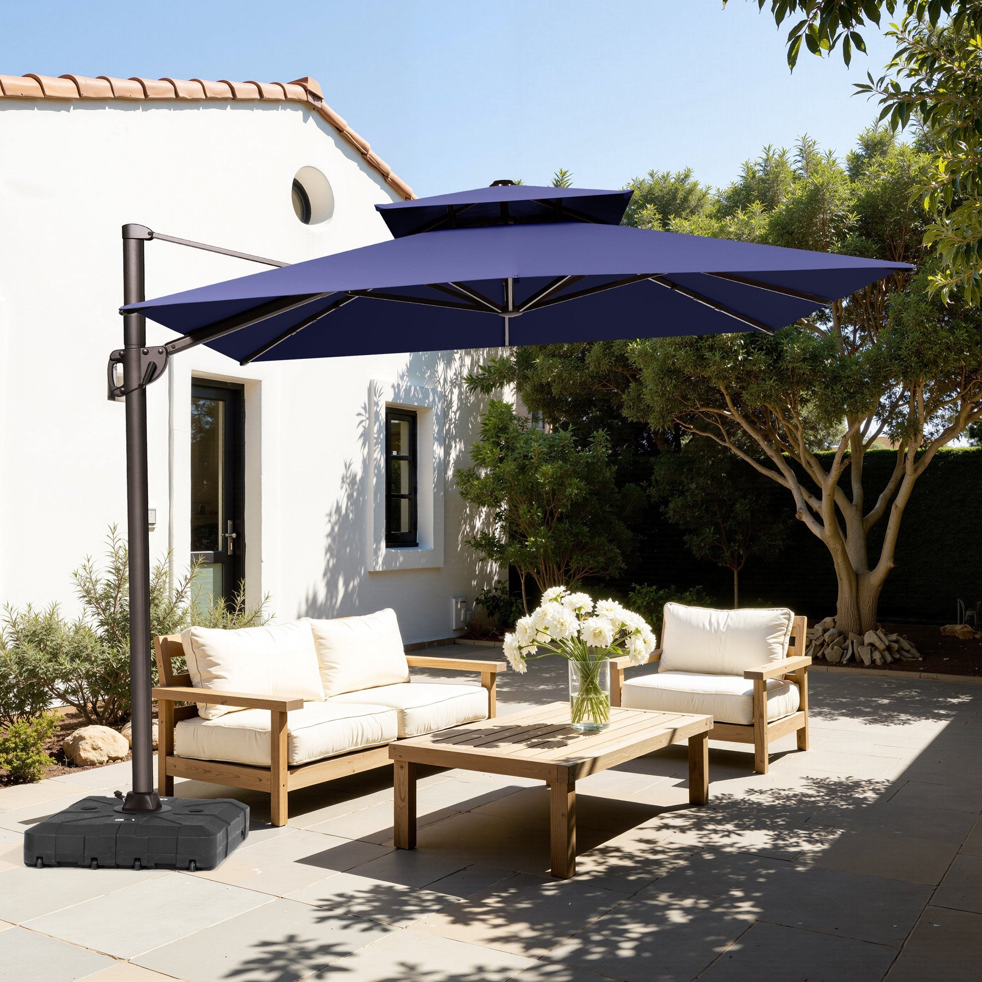 Crestlive 13x10 ft navy blue rectangular cantilever patio umbrella with LED lights shading a wooden conversation sofa set in a Spanish colonial style courtyard.