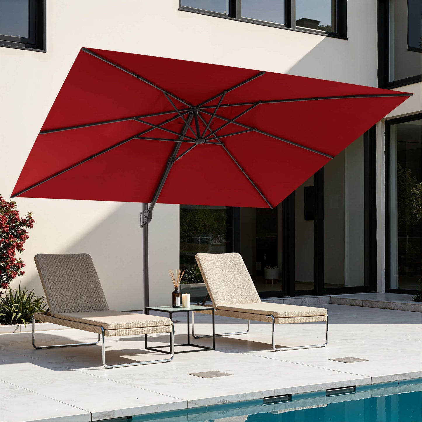 Red rectangular cantilever patio umbrella over poolside lounge chairs.