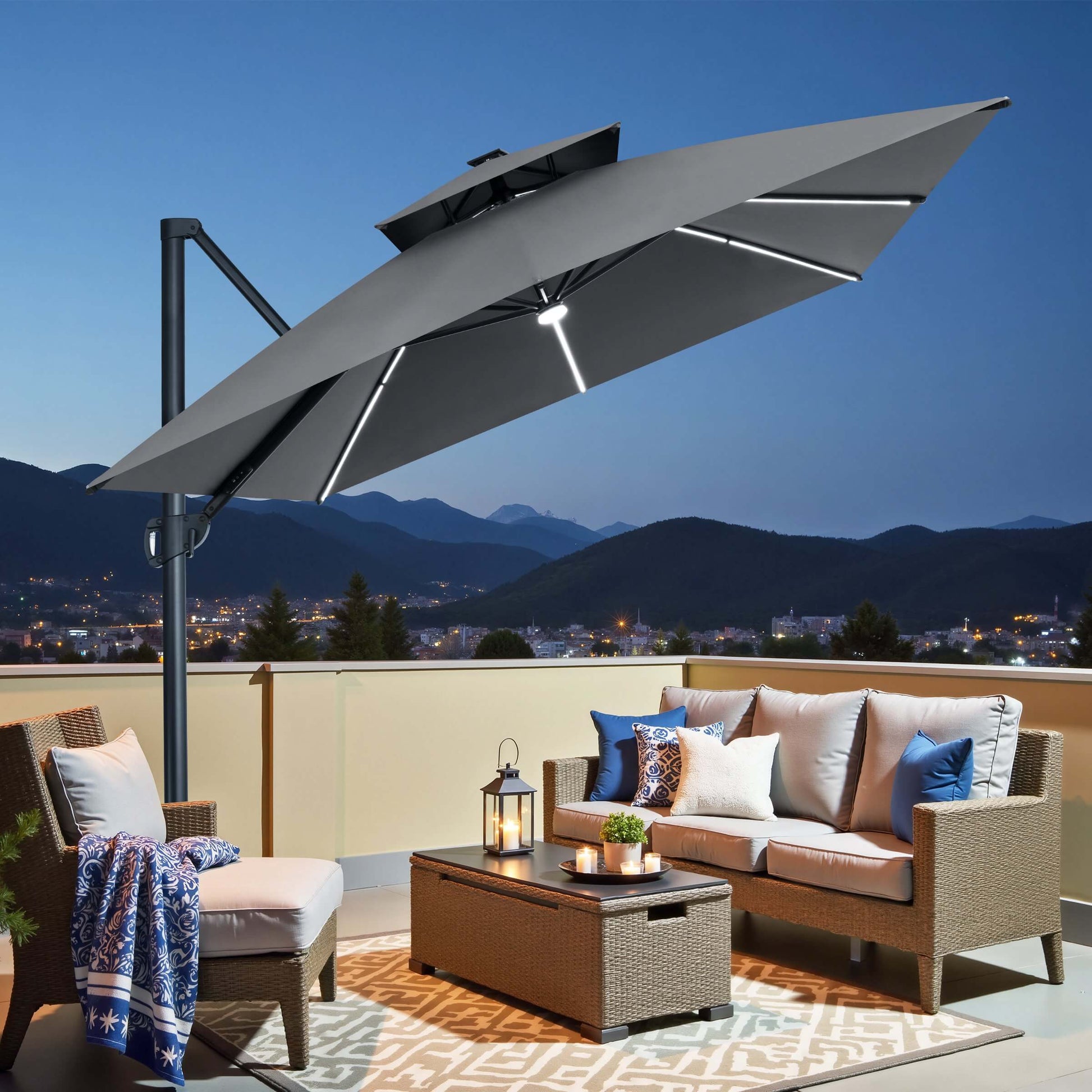 Grey square double-top cantilever patio umbrella with LED lights illuminating a balcony seating area at night.