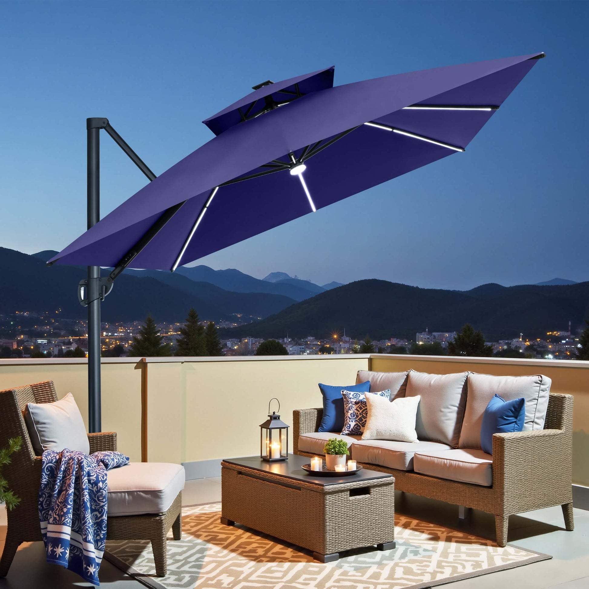 Navy blue square double-top cantilever patio umbrella with LED lights illuminating a balcony seating area at night.