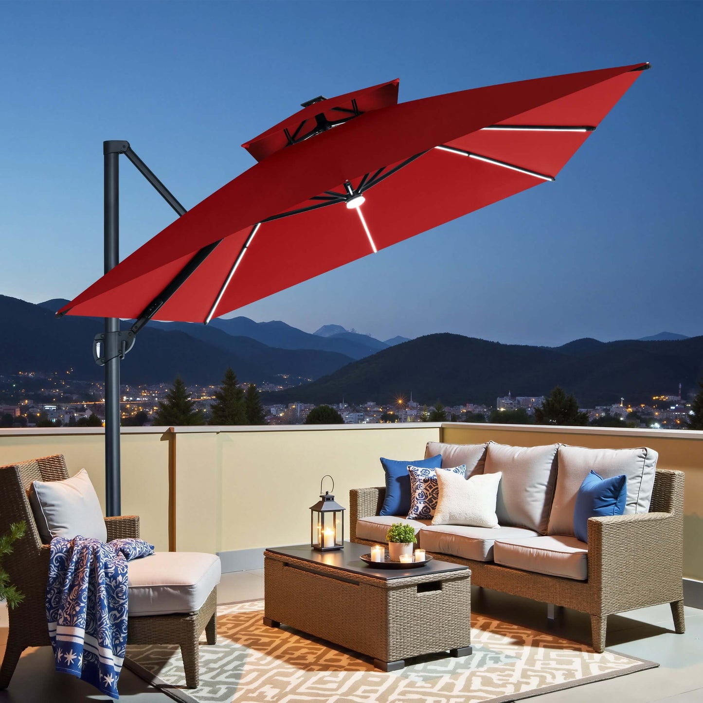 Red square double-top cantilever patio umbrella with LED lights illuminating a balcony seating area at night.