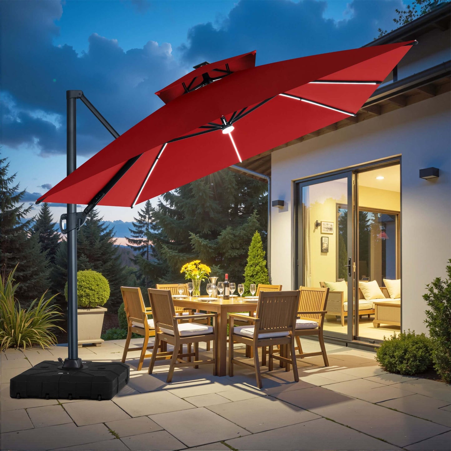 Red square double-top LED cantilever patio umbrella with wheeled base illuminating outdoor dining set at dusk.