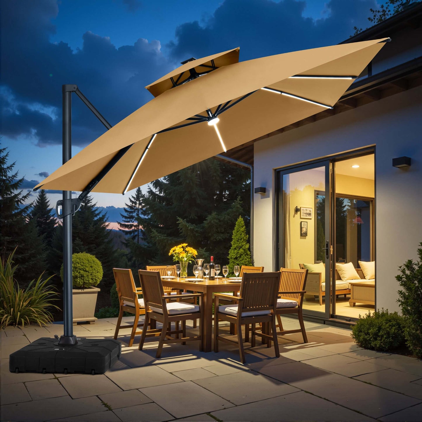 Illuminated beige square double-top cantilever patio umbrella with LED lights and rolling base over an outdoor dining set at dusk.