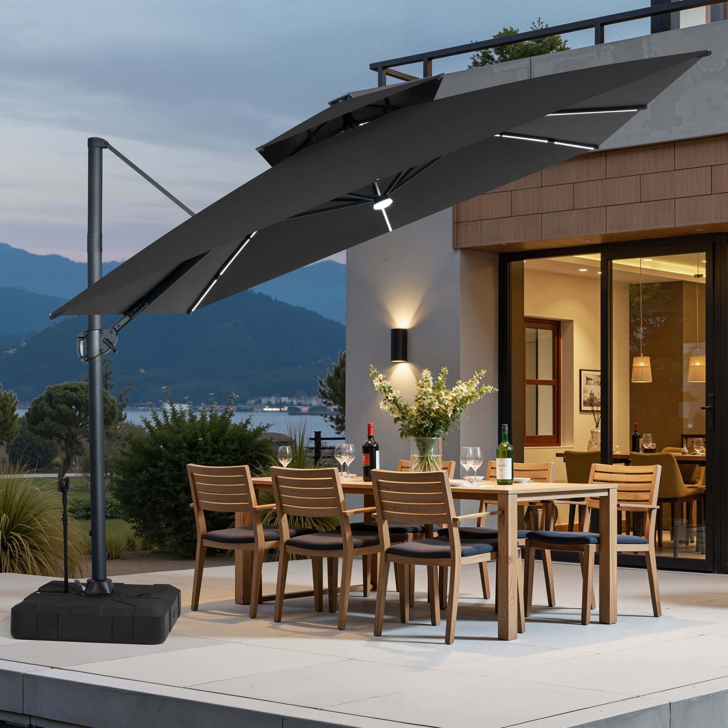Tilted black LED cantilever umbrella on pull-rod base over a patio dining set at dusk.