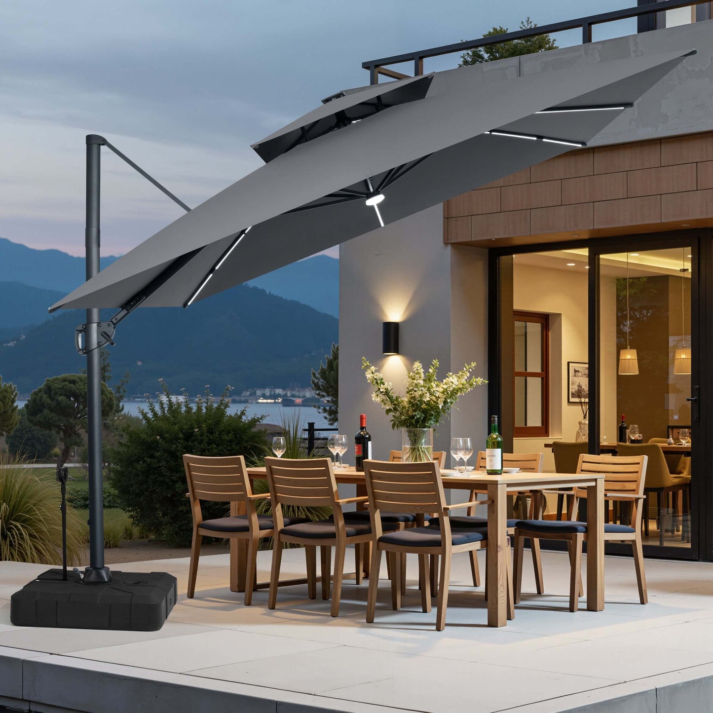 Tilted grey LED cantilever umbrella on pull-rod base over a patio dining set at dusk.