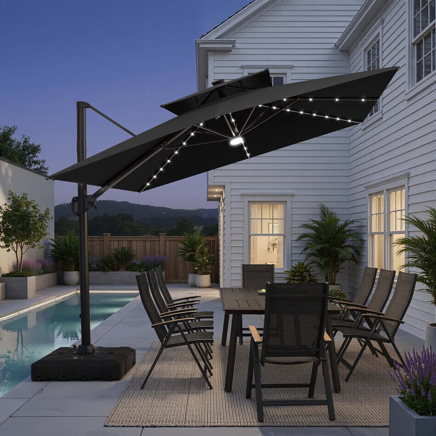 Tilted 11x9 ft black lighted cantilever patio umbrella with heavy-duty base shading a dining set by the pool