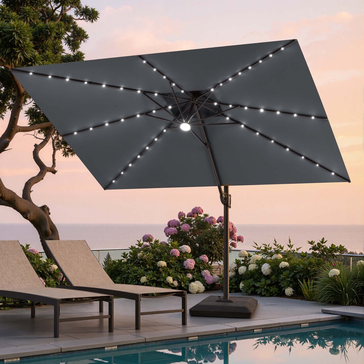 Tilted 11x9 ft grey lighted cantilever umbrella with heavy-duty base shading poolside lounge chairs at sunset ocean view