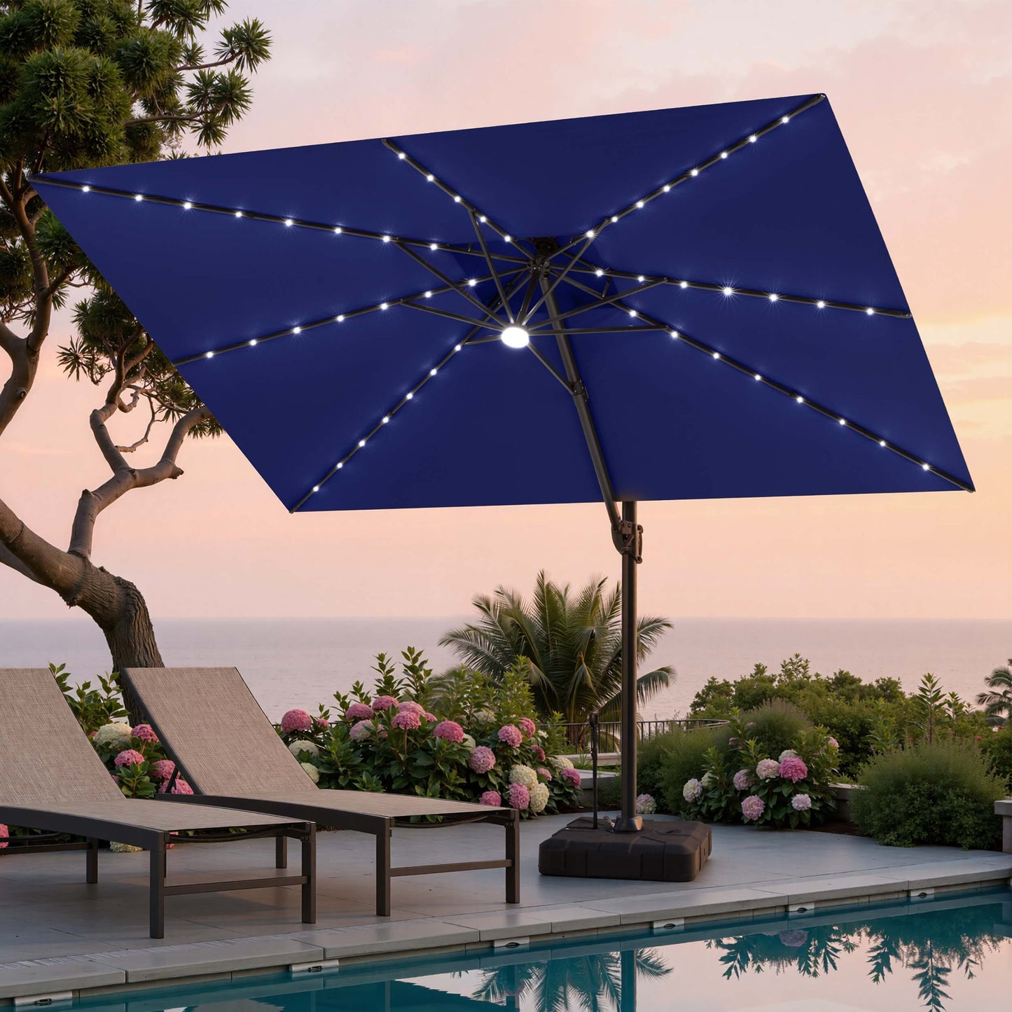 Tilted 12x9 ft navy blue lighted cantilever umbrella with wheeled base shading poolside lounge chairs at sunset