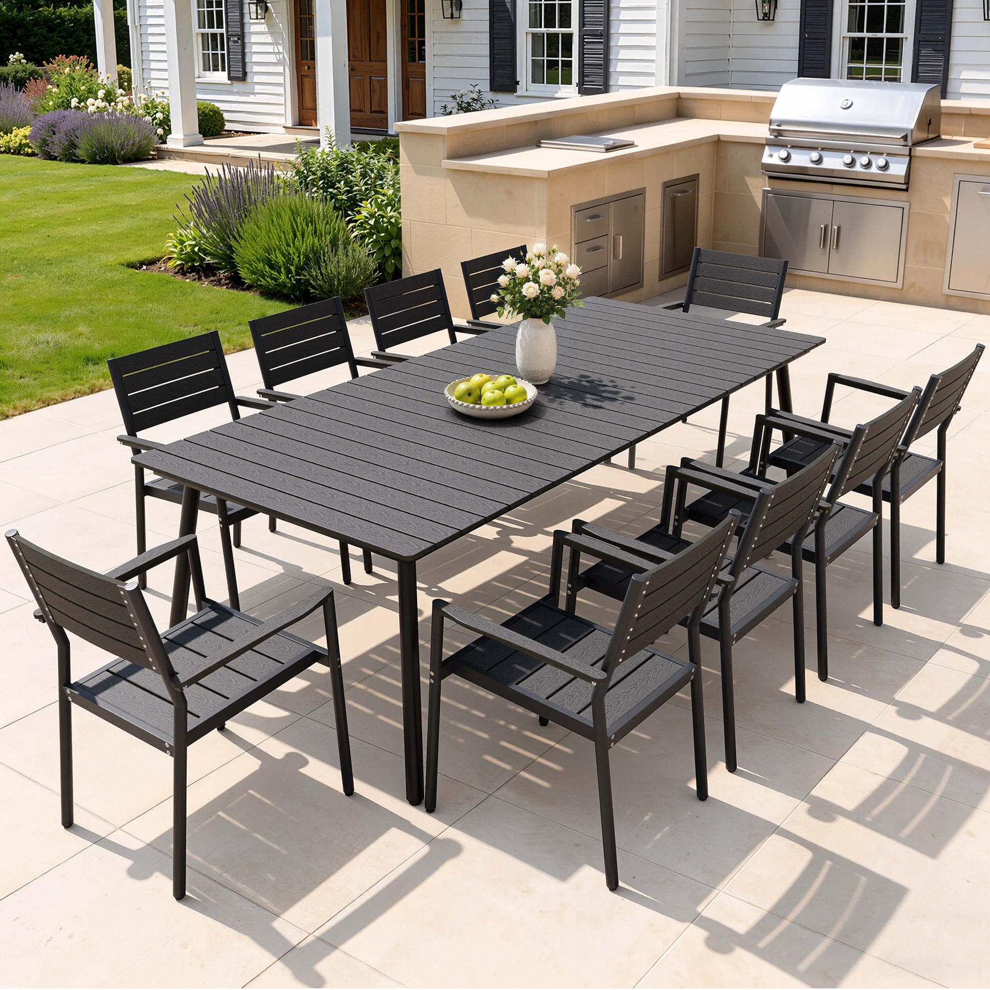 Modern 9-piece black outdoor dining set with large polywood table and 8 chairs on patio with outdoor kitchen.