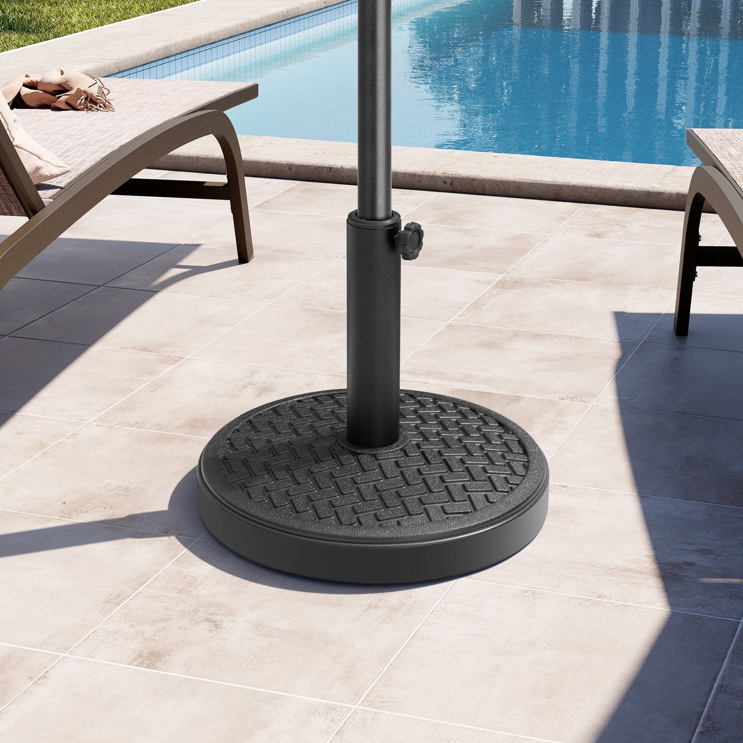 Black 30-45 lbs concrete round market umbrella base between poolside lounge chairs in bright sunlight.