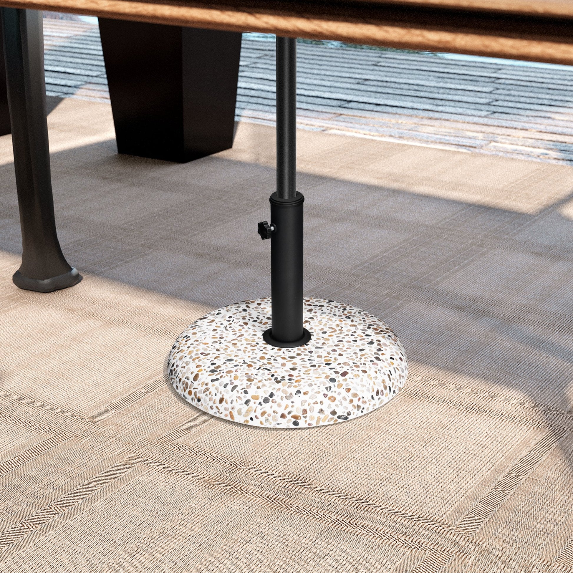 Pebble white 45 lbs heavy duty round cement umbrella base under a patio table on an outdoor rug.
