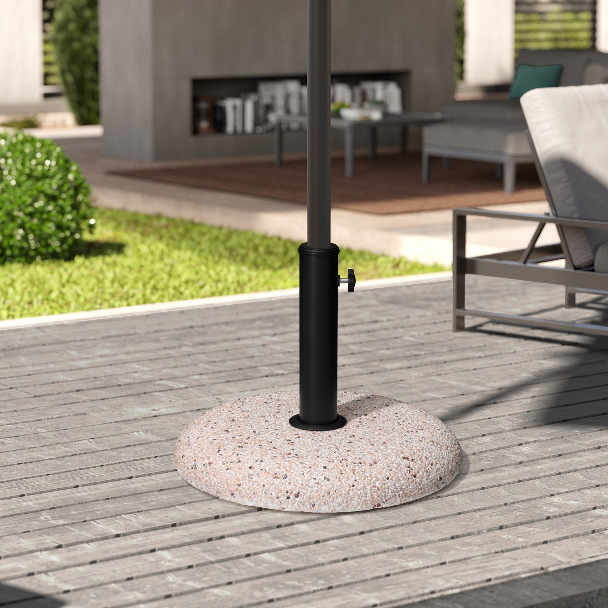 Round weighted aggregate patio umbrella stand on a grey wooden deck with outdoor furniture.