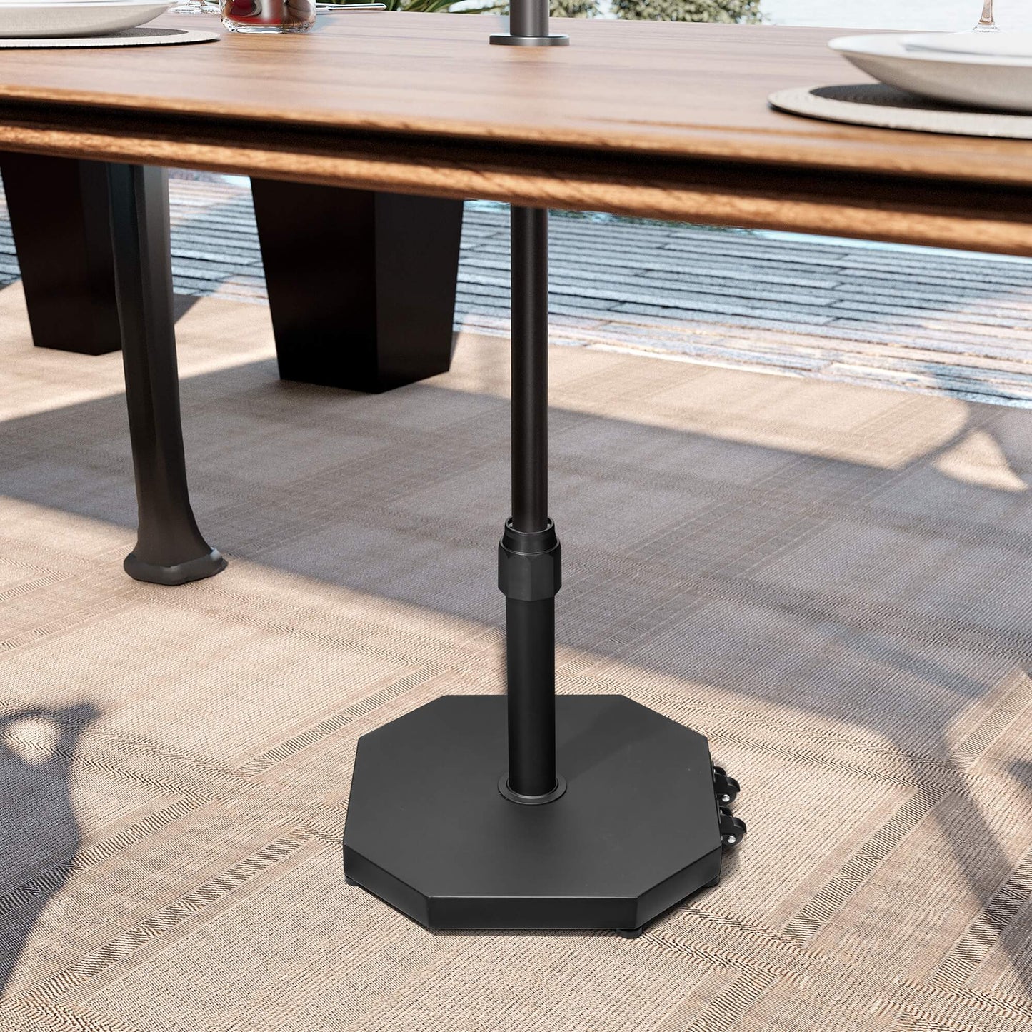 Black 40 lbs octagonal cement market umbrella base with wheels under a wooden patio dining table.