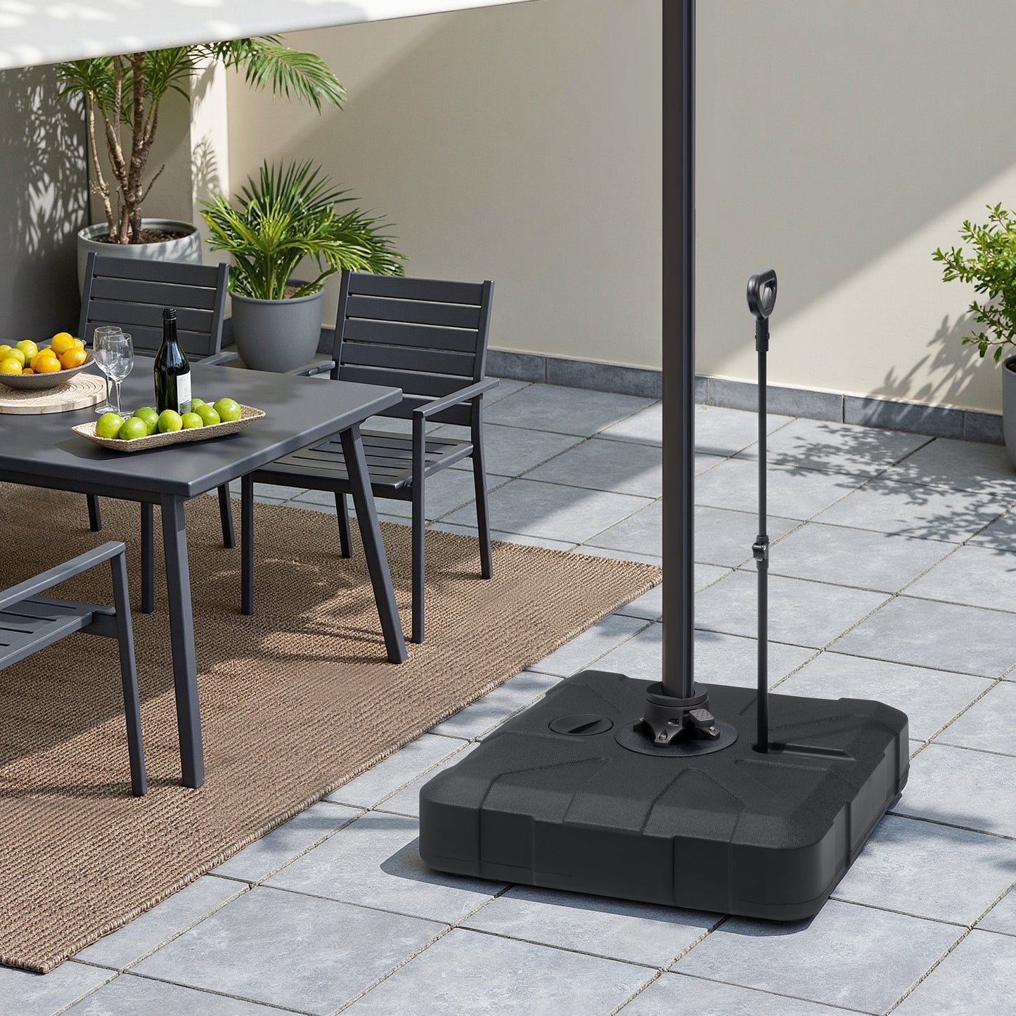 Heavy-duty fillable patio umbrella base near outdoor dining set on a bright sunlit residential terrace.