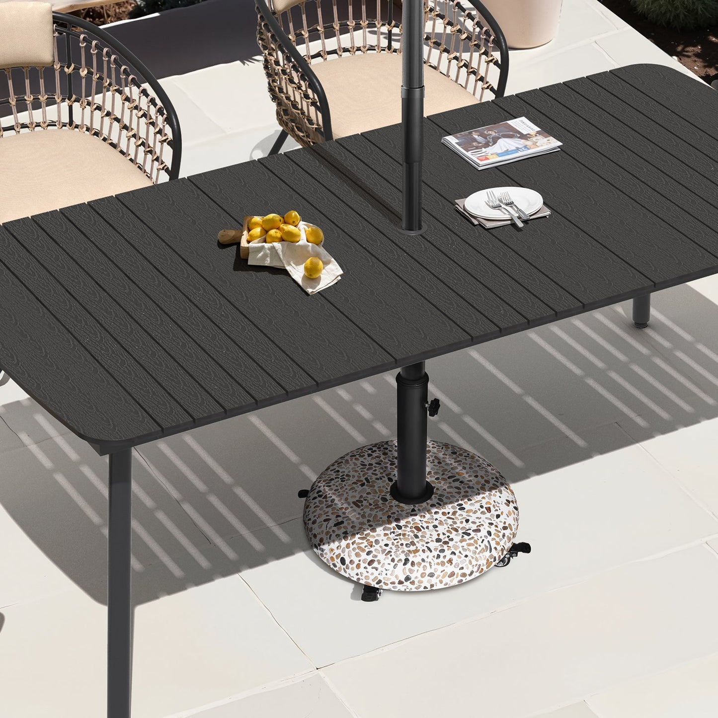 Round 45 lbs concrete cobble patio umbrella base with wheels placed under a black outdoor dining table.