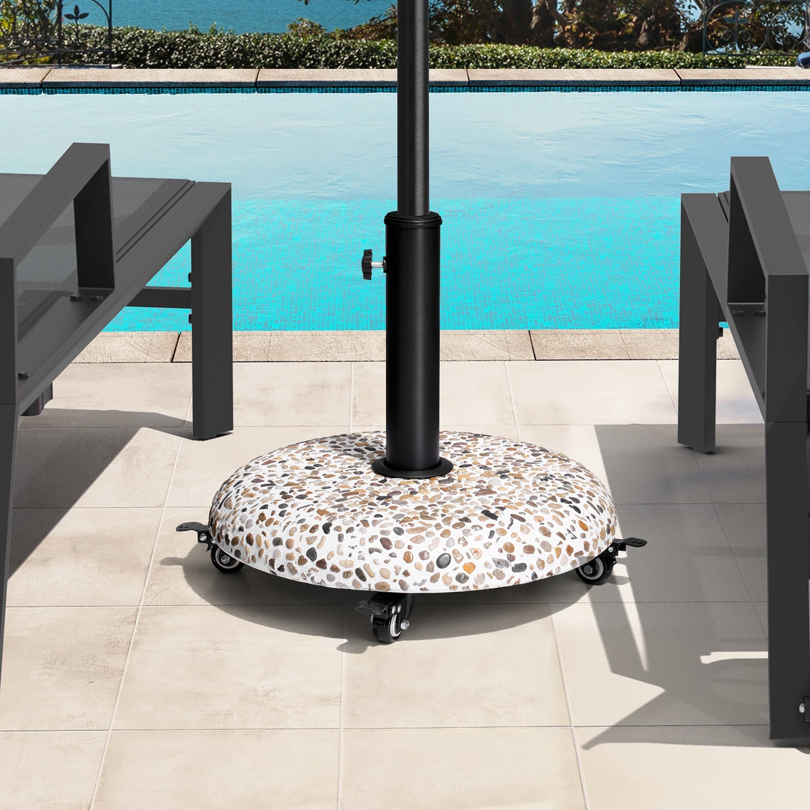 Round 45 lbs concrete cobble patio umbrella base with swivel wheels securing an umbrella by a poolside.