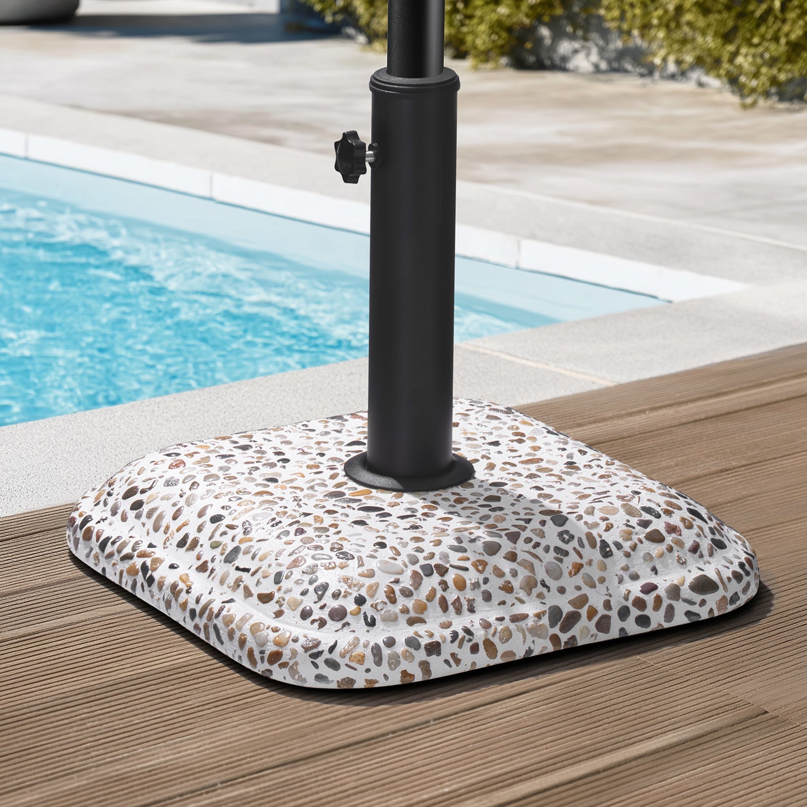 45 lbs cobble cement patio umbrella base without wheels standing on a poolside deck.