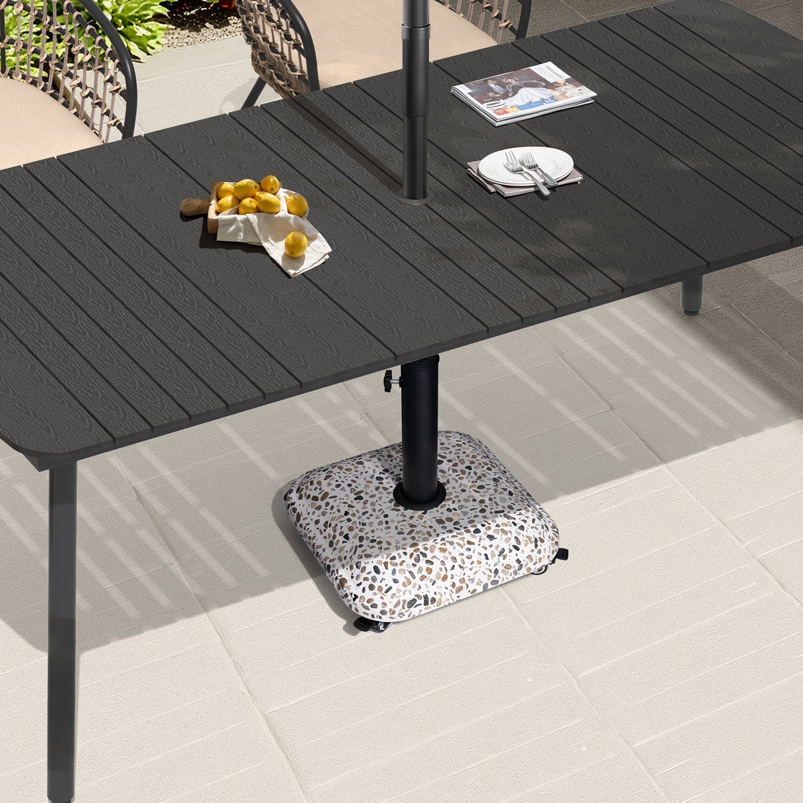 45 lbs cobble cement patio umbrella base with wheels securing an umbrella under a black dining table.