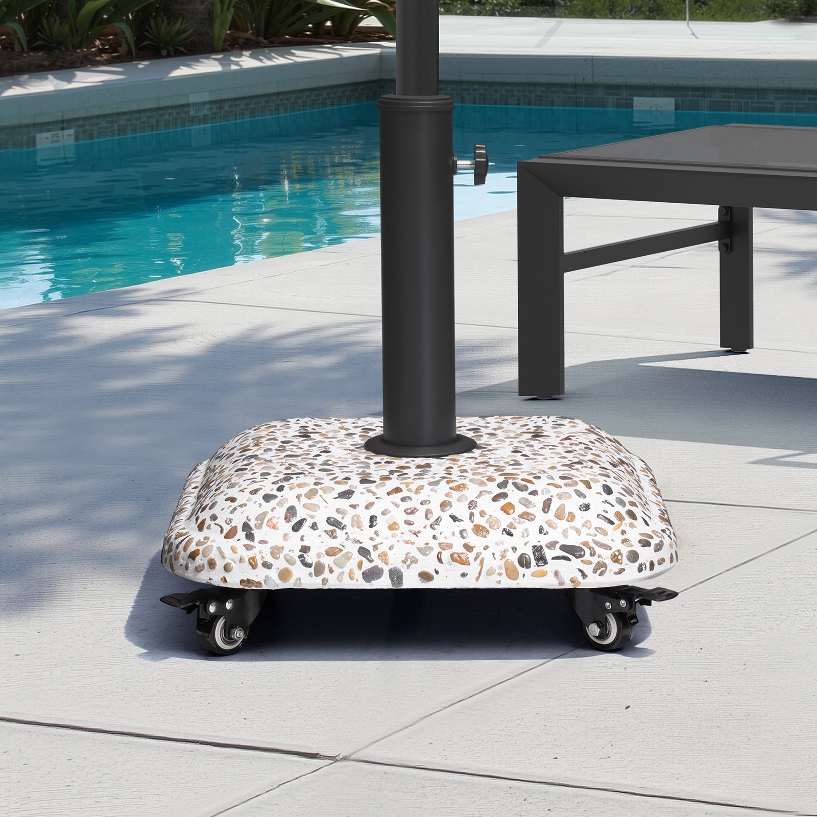 45 lbs cobble cement patio umbrella base with wheels, placed on a sunny poolside patio.